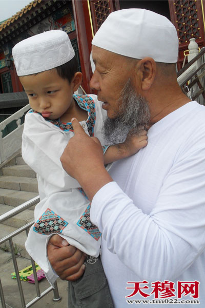 幸福的老人抱着可爱的孙子在清真寺外等候老伴儿