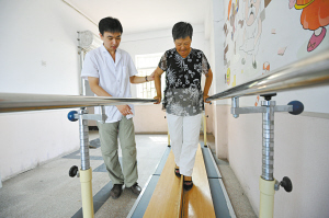  近日，天津市北辰区天穆医院开设免费康复训练室，针对因脑栓塞、脑出血造成行动不便的病人进行免费康复指导。图为大夫辅助患者在平行杠上行走。记者 常朴 摄
