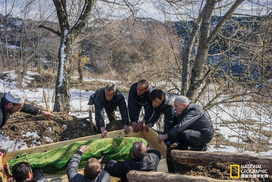 最后一程 在里贝诺沃，葬礼和婚礼一样都是需要公开操办的大事。图中的几个男人正把棺材放入墓坑。摄影：GUY MARTIN, NATIONAL GEOGRAPHIC