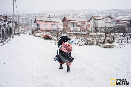 宝宝在路上 这位里贝诺沃村的波马克妇女正背着她的宝宝走在风雪中。摄影：GUY MARTIN, NATIONAL GEOGRAPHIC